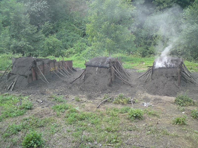 Traditional earthen charcoal kilns slowly smoking